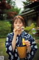 A woman in a blue and white kimono blowing bubbles.