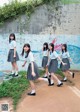 A group of young women in school uniforms walking down a sidewalk.