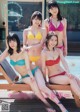 A group of women in bikinis sitting next to a swimming pool.