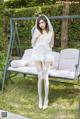 A woman in a white lingerie posing on a swing.