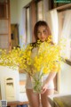 A woman holding a vase of yellow flowers in a kitchen.