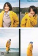 A woman in a yellow coat standing on a beach.