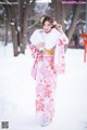 A woman in a pink kimono standing in the snow.