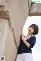 A woman leaning against a wall with her hand on her hip.