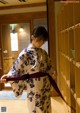 A woman in a kimono is holding a purple belt.